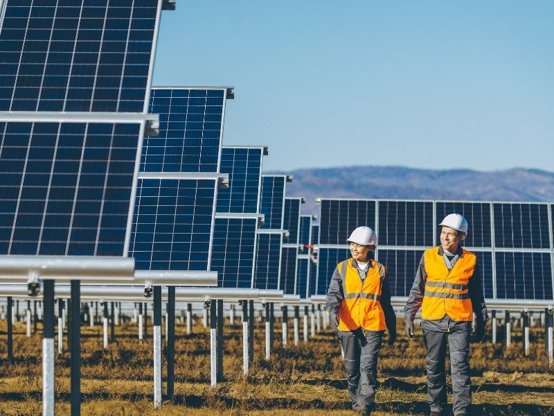 Two solar panel experts are monitoring a large solar plant system.